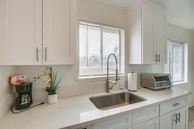 a white kitchen with a sink and a microwave at 2 Mi to Ocean! Executive-Style Oasis in Long Beach in Long Beach
