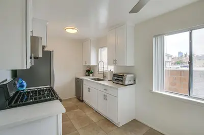 a kitchen with white cabinets and a sink and a window at 2 Mi to Ocean! Executive-Style Oasis in Long Beach in Long Beach