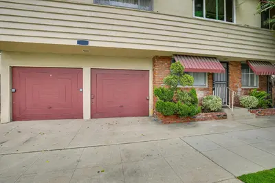 two red garage doors on the side of a house at 2 Mi to Ocean! Executive-Style Oasis in Long Beach in Long Beach