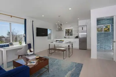 a living room with a blue couch and a kitchen at Elegant Ocean View Studio in Prime Santa Monica Location in Los Angeles