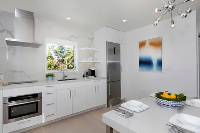 a kitchen with white cabinets and a table with a bowl of fruit at Elegant Ocean View Studio in Prime Santa Monica Location in Los Angeles