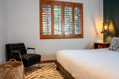 a bedroom with a bed and a chair and a window at The Mighty Pines Retreat + Large Patio + BBQ+View! in Lake Arrowhead