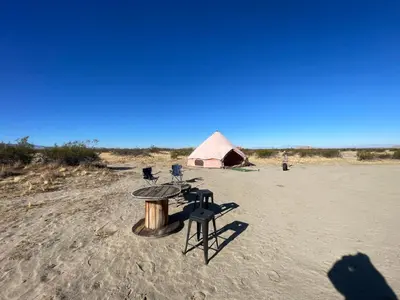 a table and chairs and a tent in the desert at New Yurt City in Lake Los Angeles