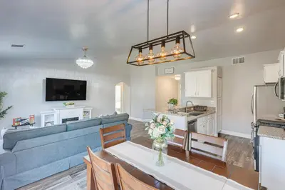 a living room with a blue couch and a kitchen at Bakersfield Home with Pool Table, Cornhole and More! in Bakersfield