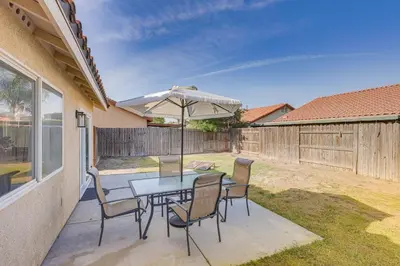 a patio with a table and chairs and an umbrella at Bakersfield Home with Pool Table, Cornhole and More! in Bakersfield