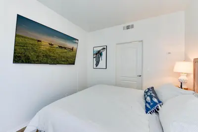 a white bedroom with a bed and a tv on the wall at Cozy Unit Conveniently Located Pool View in Los Angeles