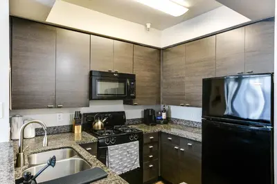 a kitchen with wooden cabinets and a black refrigerator at Cozy Unit Conveniently Located Pool View in Los Angeles