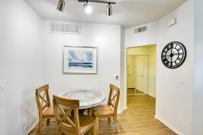 a dining room with a table and chairs and a clock at Cozy Unit Conveniently Located Pool View in Los Angeles
