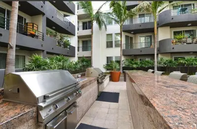 an outdoor kitchen with a grill and a building at Cozy Unit Conveniently Located Pool View in Los Angeles