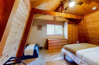 a attic bedroom with a bed and a window at Hidden Wonder in Crestline