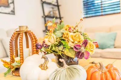 a table with pumpkins and a vase with flowers at Newly Remodeled 3B2B House in Glendora
