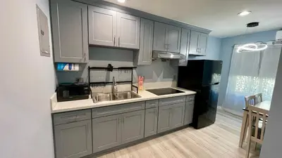 a kitchen with white cabinets and a black refrigerator at Quintessence ApartHotel in Los Angeles
