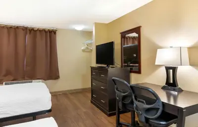 a hotel room with a desk and a bed and a television at Relax Suites Extended Stay - La Mirada in La Mirada