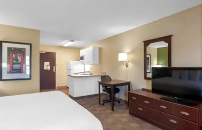 a hotel room with a bed and a desk and a kitchen at Relax Suites Extended Stay - La Mirada in La Mirada