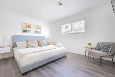 a white bedroom with a bed and a chair at Enjoy Alhambra Night Life at 2BR Apt in Alhambra