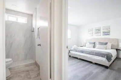 a white bedroom with a bed and a shower at City Retreat Minutes to DT in Alhambra