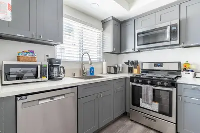 a kitchen with stainless steel appliances and gray cabinets at City Retreat Minutes to DT in Alhambra