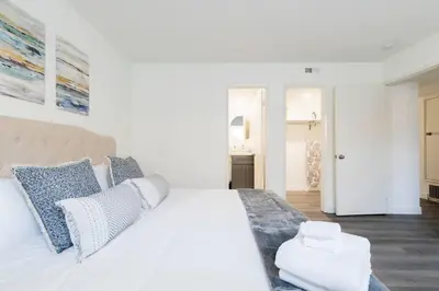 a white bedroom with a large bed with blue pillows at City Retreat Minutes to DT in Alhambra