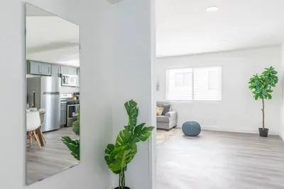 a living room with white walls and a mirror at City Retreat Minutes to DT in Alhambra