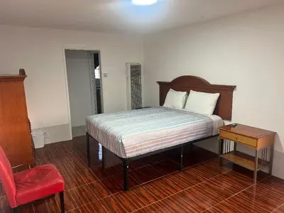 a bedroom with a bed and a red chair at Silver Sands Motel in Ventura