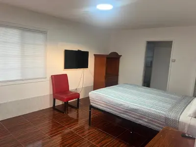 a bedroom with a bed and a red chair at Silver Sands Motel in Ventura