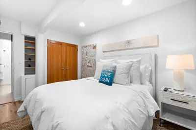 a white bedroom with a bed with a blue sign on it at Coastal Serenity in Malibu