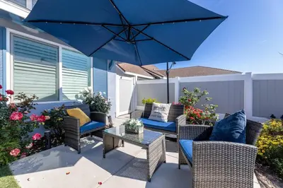 a patio with chairs and a table with a blue umbrella at Luxe and Modern South Bay ADU in Carson