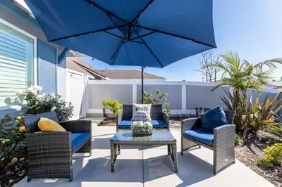 a patio with a table and a blue umbrella at Luxe and Modern South Bay ADU in Carson