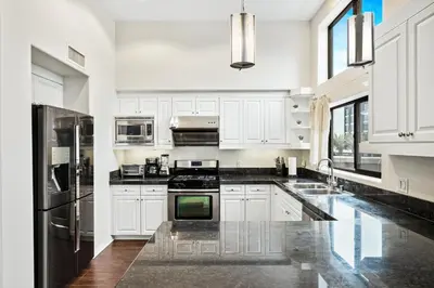 a kitchen with white cabinets and black appliances at Ultimate LA Vacation 2BR w Pool Above Shops in Monterey Park