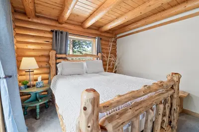 a log cabin bedroom with a bed and a desk at Lakeview Lodge - Across the street from the lake and Boulder Bay Park! in Big Bear Lake