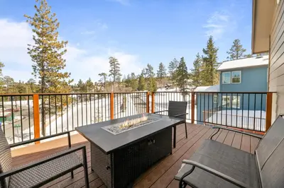 a balcony with a table and chairs on a deck at Pine Meadow - Game Room with pool table, foosball & shuffleboard! in Big Bear Lake