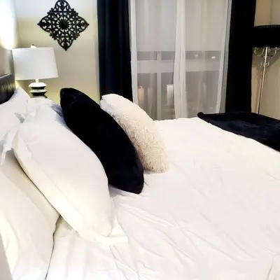 a white bed with black pillows and a window at Spacious 22, Wi-fi, Pool, Hot Tub, 24hr Gym in Los Angeles