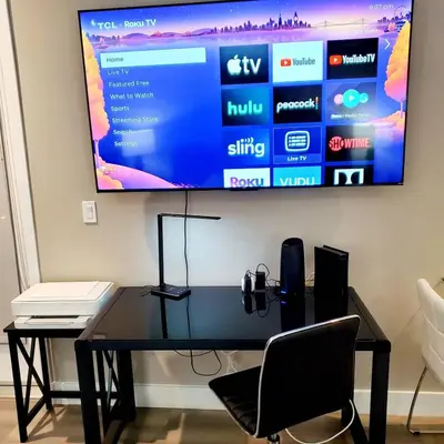 a television hanging on a wall with a desk and chairs at Spacious 22, Wi-fi, Pool, Hot Tub, 24hr Gym in Los Angeles