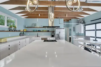 a kitchen with white counters and wooden ceilings at NEW BEACH Pool Home, New Industrial OCEAN Vibe, Hot Tub, Pool, Views in El Segundo