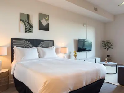 a bedroom with a large white bed and a tv at City View Suite - DTLA by Monthier in Los Angeles