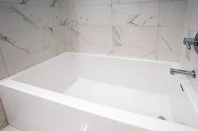 a white bath tub in a white tiled bathroom at City View Suite - DTLA by Monthier in Los Angeles