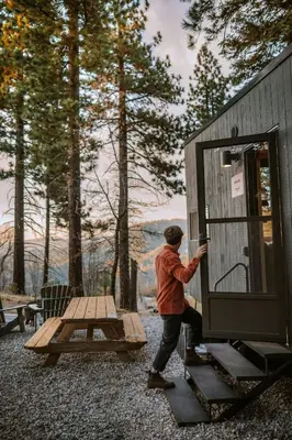 a man opening the door of a tiny house at Postcard Cabins Big Bear, Outdoor Collection by Marriott Bonvoy in Running Springs