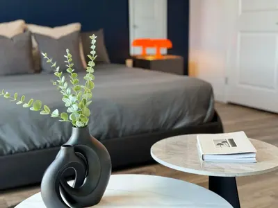 a black vase with flowers on a table next to a bed at Cosmopolitan Hollywood Home DTLA view Parking - 10mins to Universal Studios in Los Angeles