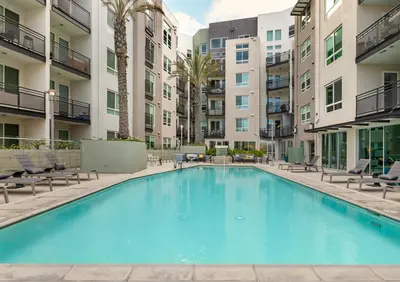 a large swimming pool with chairs and buildings at Cozy Home in LA - Free Parking 10 Min to Cedars in Los Angeles