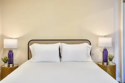 a bed with white pillows and two purple lamps at Los Angeles Suite LACMA in Los Angeles