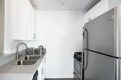 a white kitchen with a stainless steel refrigerator at Brentwood Studio w Pool nr UCLA Whole Foods LAX-290 in Los Angeles