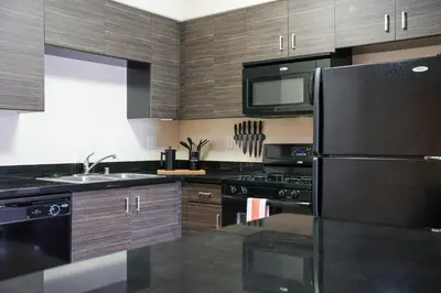 a kitchen with wooden cabinets and a black refrigerator at Los Angeles Modern Studio in Los Angeles