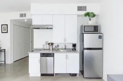 a white kitchen with a refrigerator and a microwave at Suite Little Tokyo Los Angeles in Los Angeles