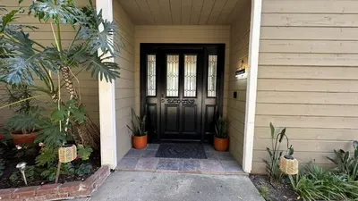 a black front door of a house with plants at Panorama Tropical Resort & Spa with Sunset City View in Santa Ana