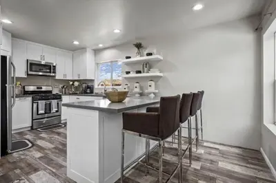 a kitchen with white cabinets and a counter with bar stools at Spacious family Guesthouse private entry near six flags in Santa Clarita