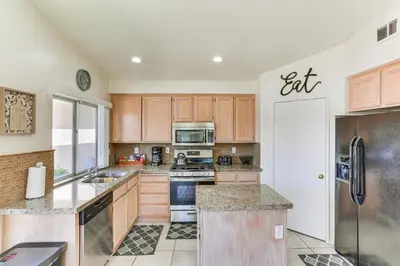 a kitchen with wooden cabinets and a white refrigerator at Victorville Home with Large Yard and Charcoal Grill! in Victorville