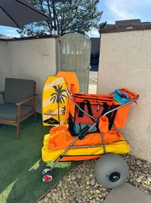 a luggage cart sitting on the grass next to a chair at Carpinteria Beach Studio Condo in Carpinteria
