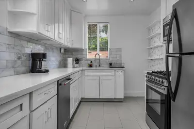 a white kitchen with white cabinets and a black refrigerator at Chic Charming 2-Bedroom with office in the WeHo in Los Angeles