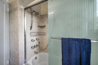 a bathroom with a shower and a bath tub with a blue towel at Chic Charming 2-Bedroom with office in the WeHo in Los Angeles