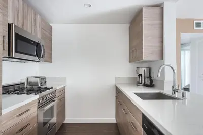 a kitchen with wooden cabinets and a stove top oven at Blueground Hollywood gym near Walk of Fame LAX-1217 in Los Angeles
